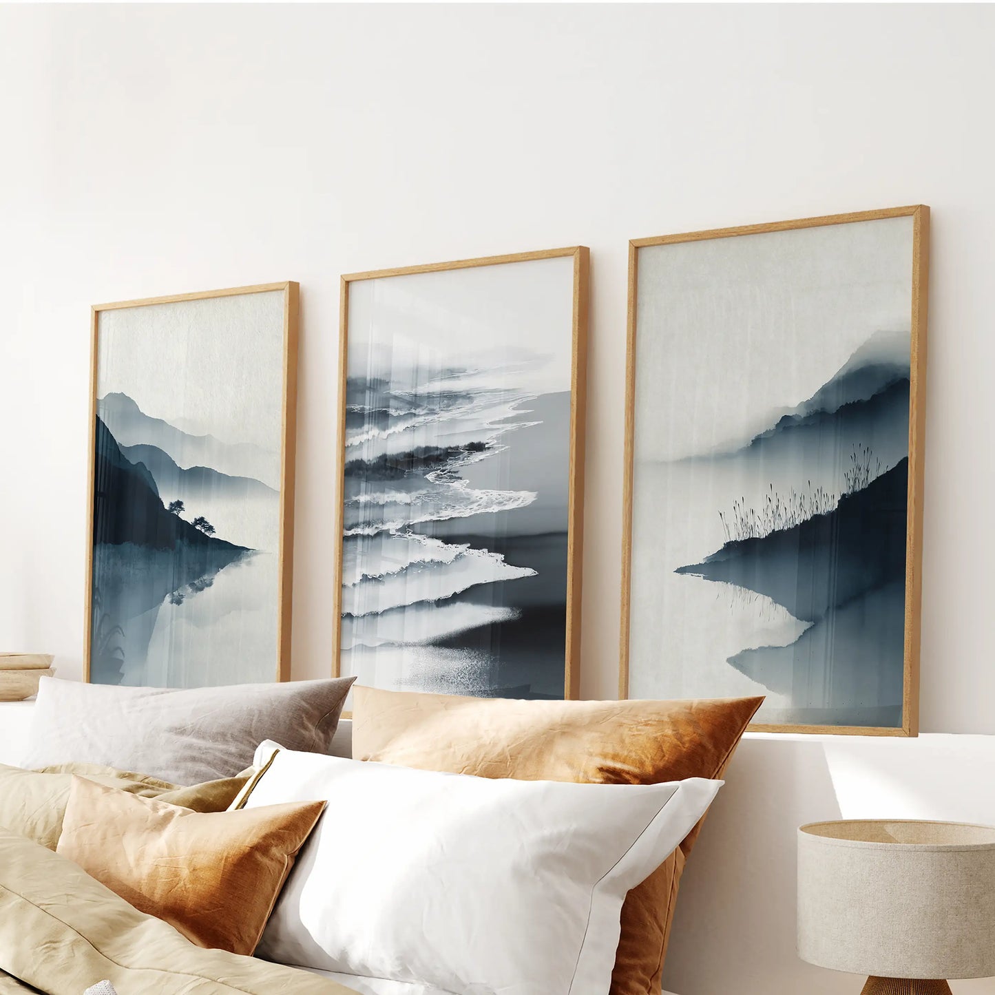 Three minimalist shoreline prints in natural-wood frames rest above the headboard, adding composed coastal balance to the bedroom.