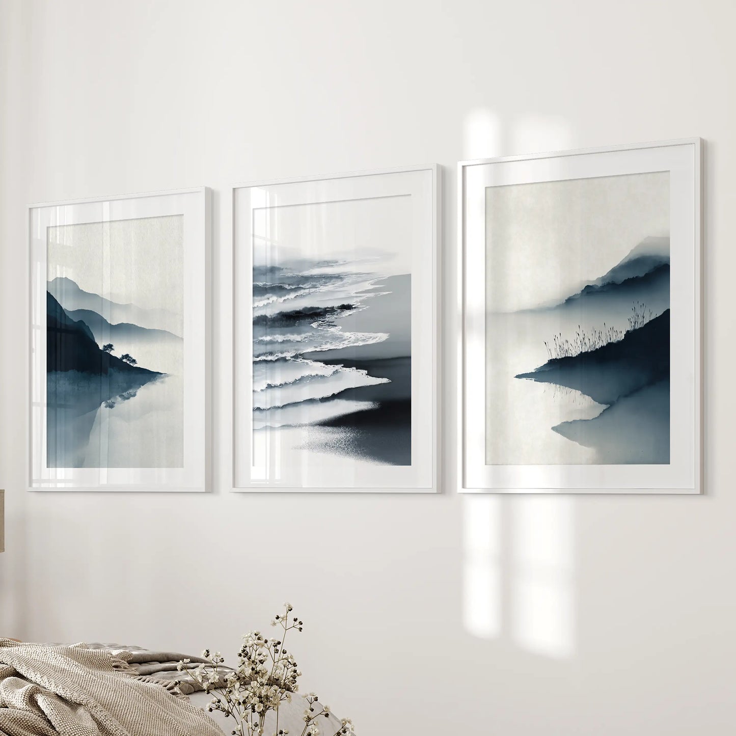 Three seascape pictures in white-matted frames line the bedroom wall by the bed, lending a simple, modern coastal ease.
