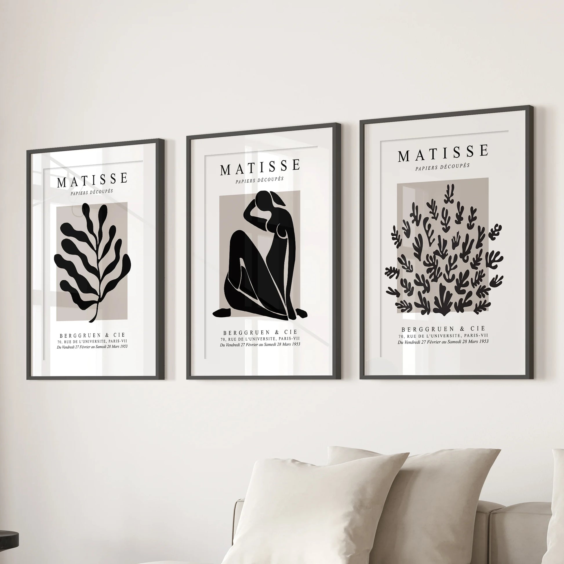 Three vintage-style posters in black matted frames form a balanced gallery wall above the lounge couch.