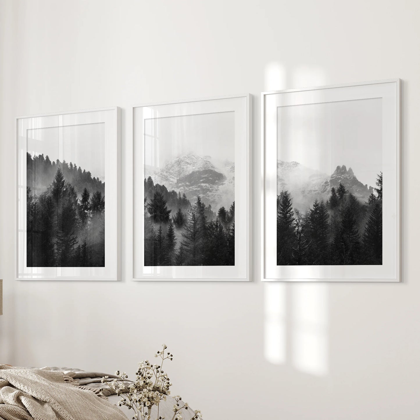 Three mist-softened tree prints bordered by white wide-matted frames bring gentle texture to a bedroom wall near the bed.