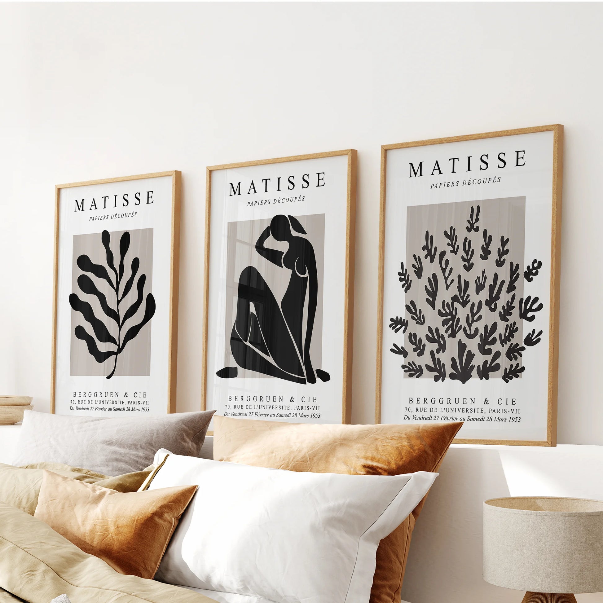 Three wood-framed vintage posters form a warm graphic trio above the bedroom headboard.