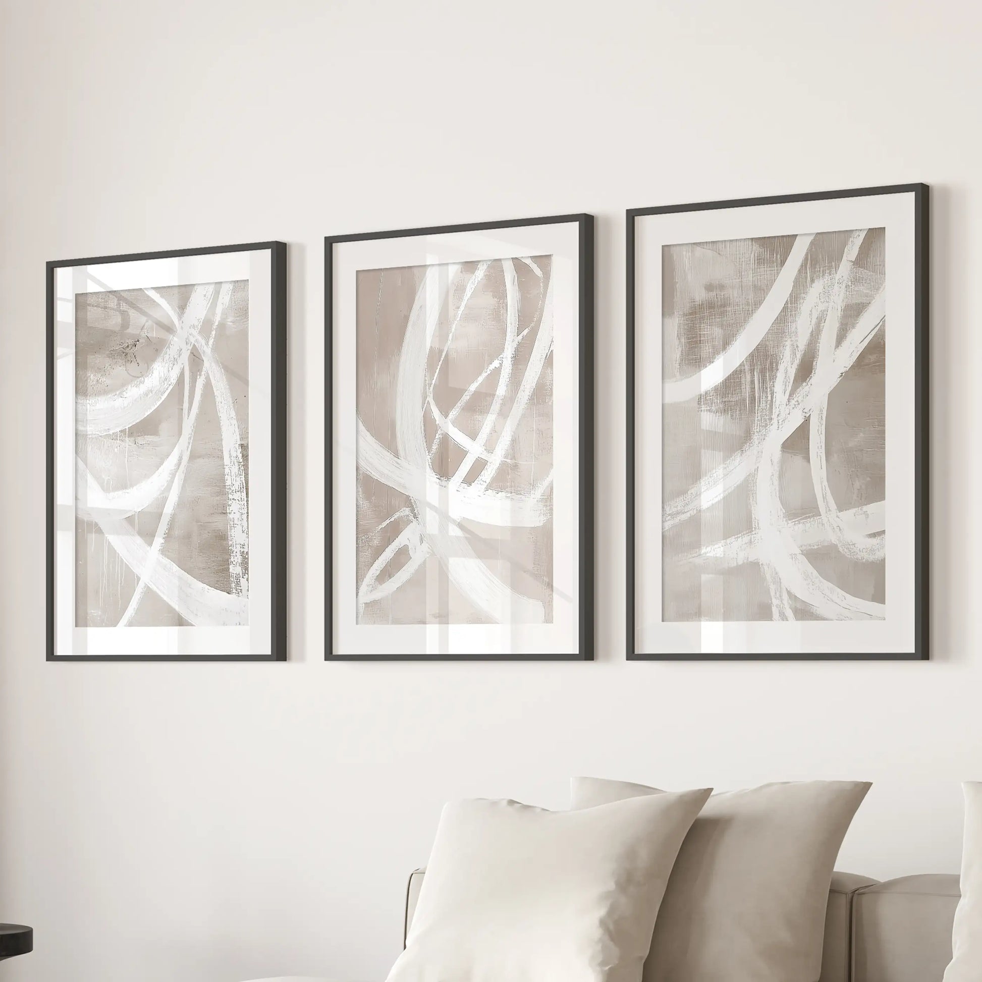 Modern abstract forms framed prints, a trio in black frames with mats, hang over the sofa and anchor the living room seating.