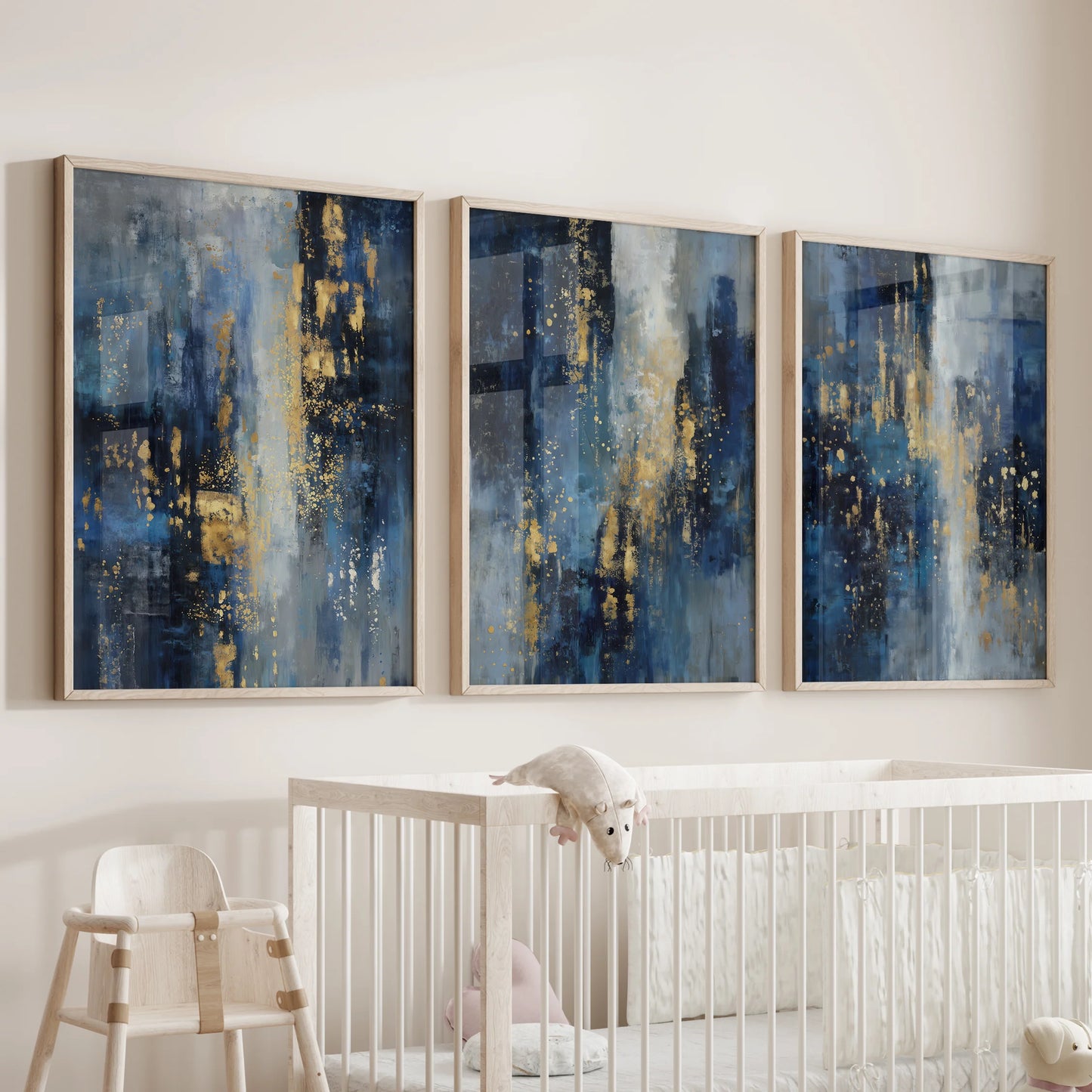 An oak-framed poster trio in blue and gold tones hangs over the crib, forming a soft focal wall for the infant room.