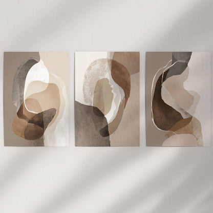 Unframed posters forming a three-piece set of organic shape studies float on a blank wall, giving a pared-back boho feel in clay hues.