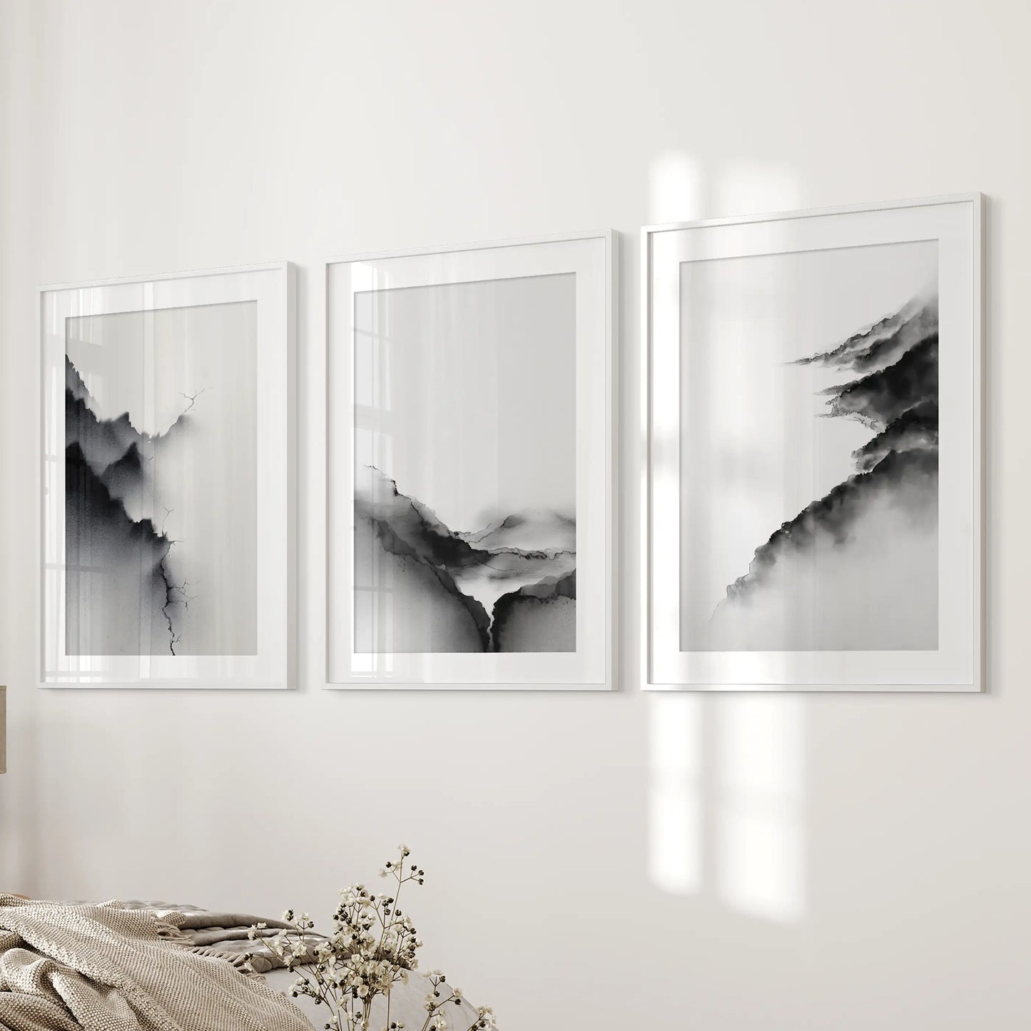 A trio of white-framed wall art prints with wide mats displays black-and-white abstract mountains beside the bed for a refined tone.