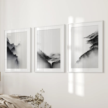 A trio of white-framed wall art prints with wide mats displays black-and-white abstract mountains beside the bed for a refined tone.