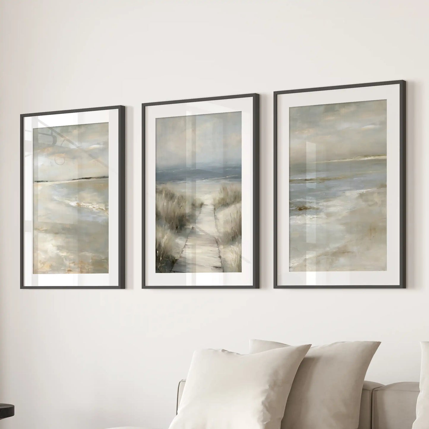 Dune grass shoreline trio of prints in black frames with wide mats brings airy coastal wall art to the living room, styled behind the couch.
