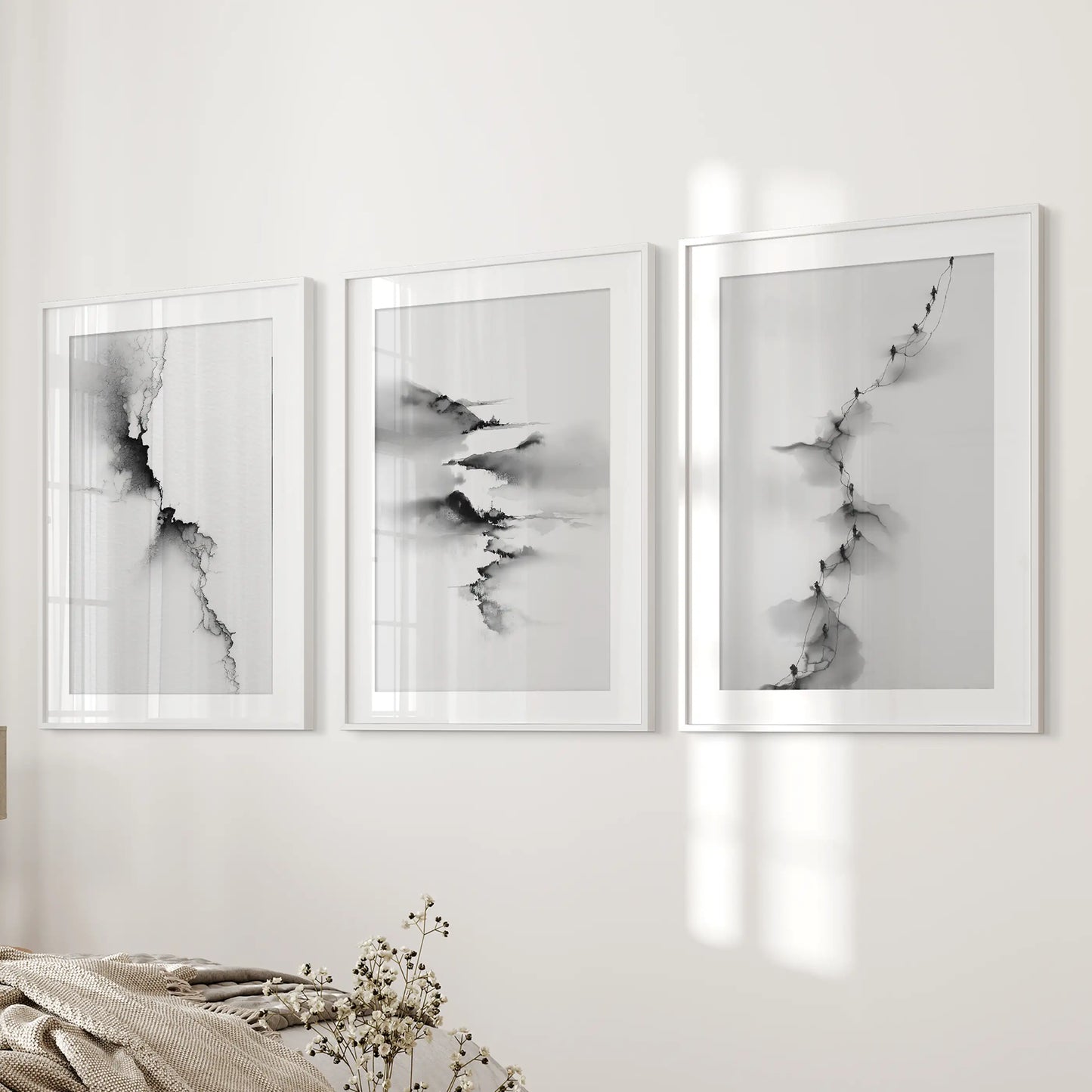 Black-and-white abstract landscape prints, a three-piece set with white frames and wide mats, line the wall next to the bed for a restful touch.