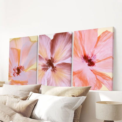 Abstract pink and coral flowers cover three canvases above a bed.