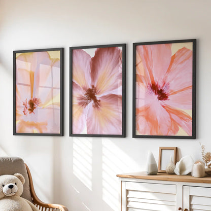 Above a dresser, three black-framed prints show pink and coral flower close-ups.