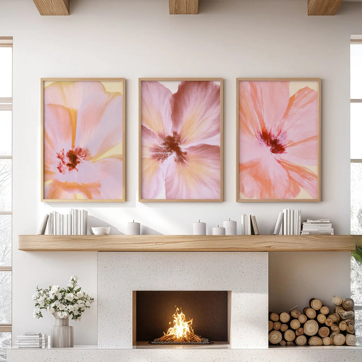 Above the fireplace mantel, three oak-framed prints show loose pink, coral and pale yellow brushstrokes forming broad flower petals.