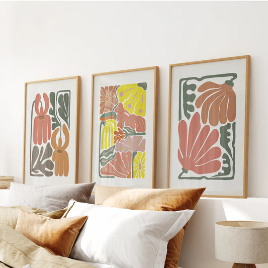 Minimalist floral illustrations form a 3-piece wall art set above the bed, paired with thin wood frames that warm the terracotta blooms with a natural touch.