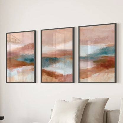 A trio of framed wall art featuring textured minimalist forms lines the family room wall in black frames behind the couch.