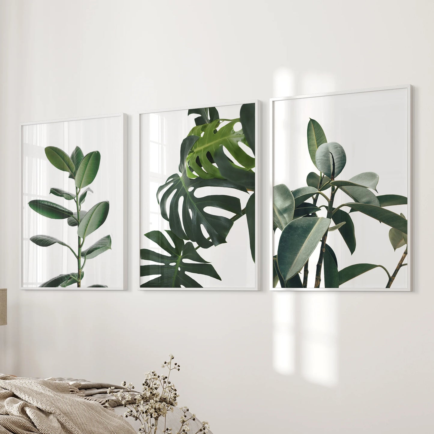 A three-panel nature art set in slim white frames lends modern botanical calm along the bedside wall of the bedroom.