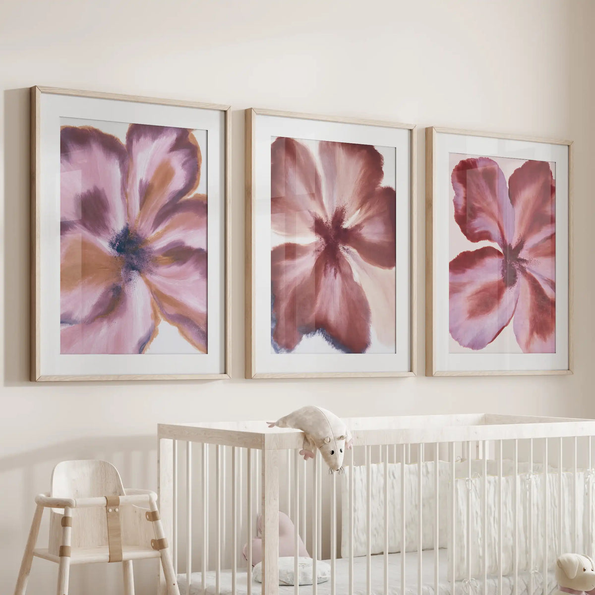 Burgundy abstract flower wall art, a three-piece set in oak frames with white mats above a crib.