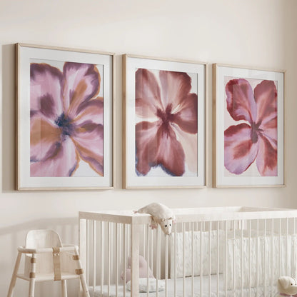 Burgundy abstract flower wall art, a three-piece set in oak frames with white mats above a crib.