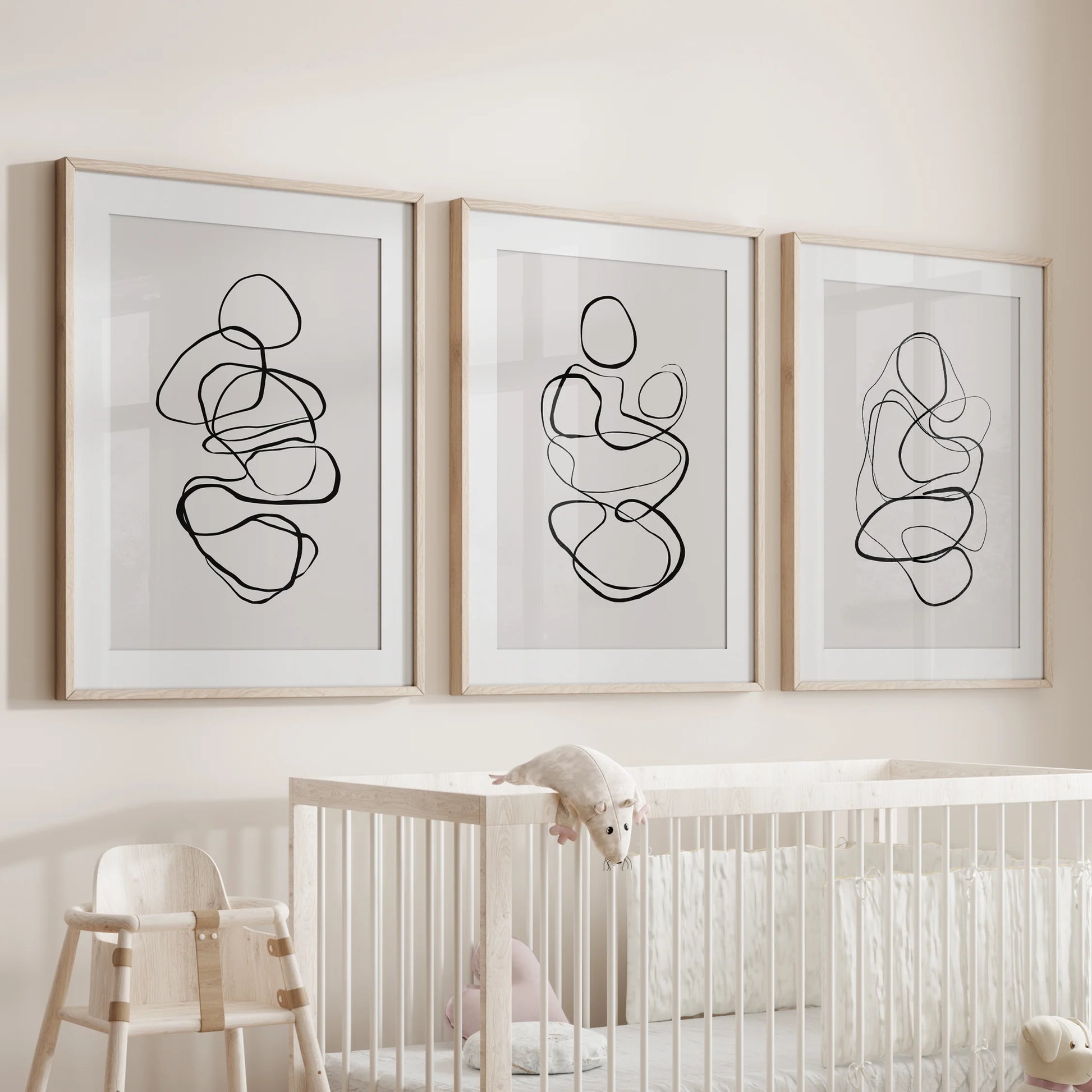Minimalist contour art, a 3-piece wall art series, rests in wood matted frames for the infant room, hanging gently over the cot.