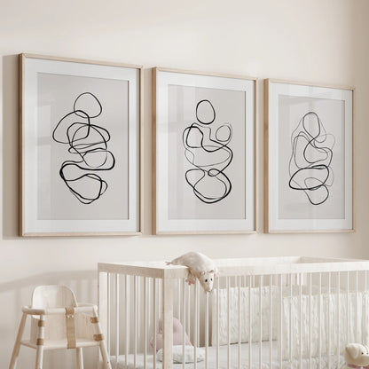 Minimalist contour art, a 3-piece wall art series, rests in wood matted frames for the infant room, hanging gently over the cot.
