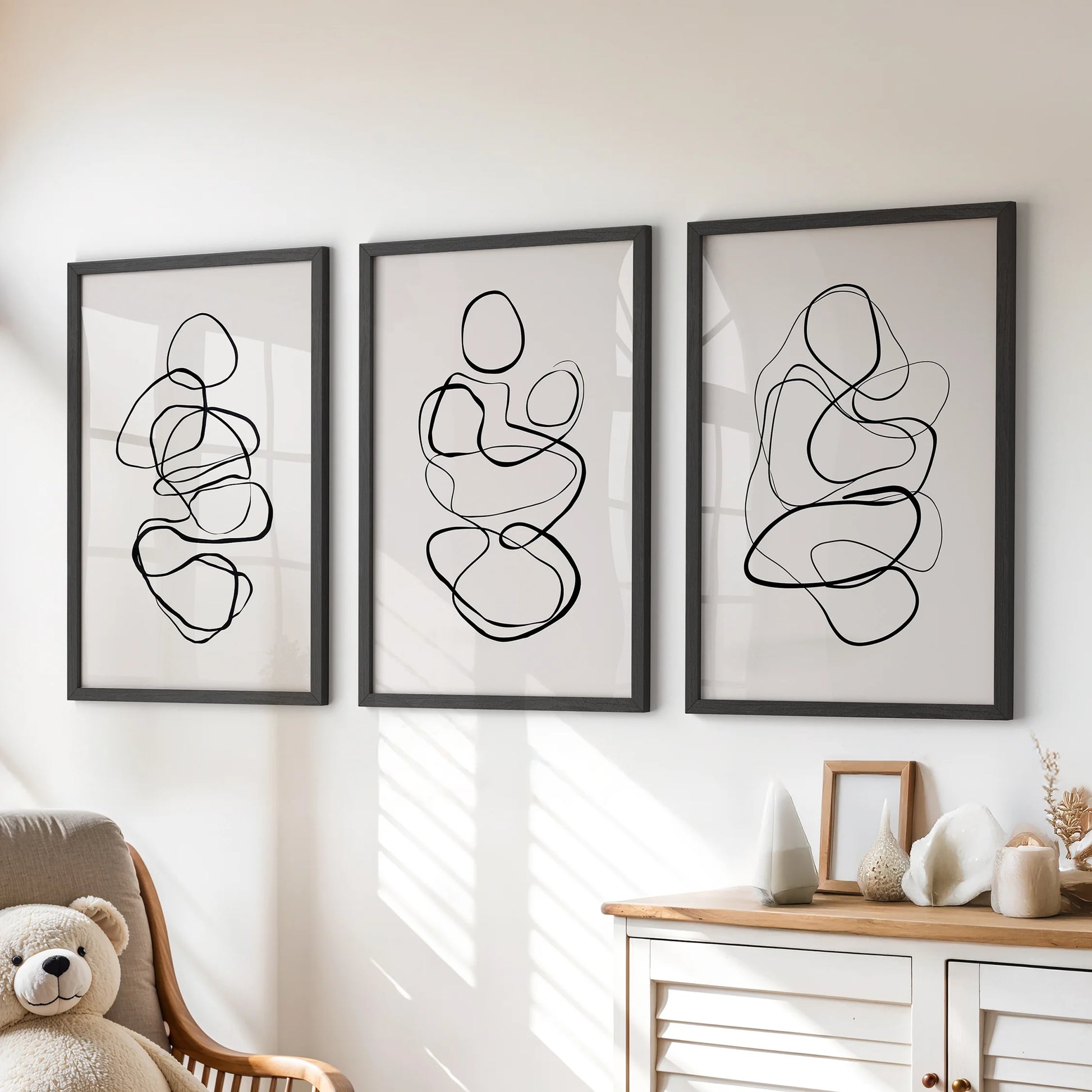 Three-piece black-framed wall decor with abstract scribbles infuses the playroom above the chest of drawers with calm modern energy.