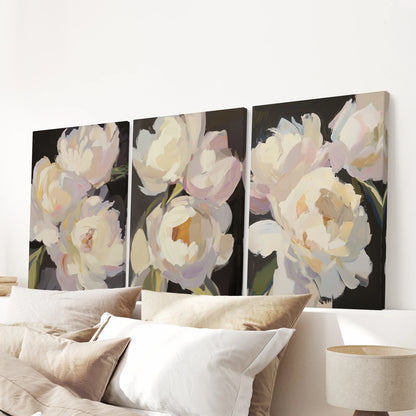 Three canvas prints of pink and white peonies float over the bedroom bed, their dark backdrop making each soft bloom quietly glow.