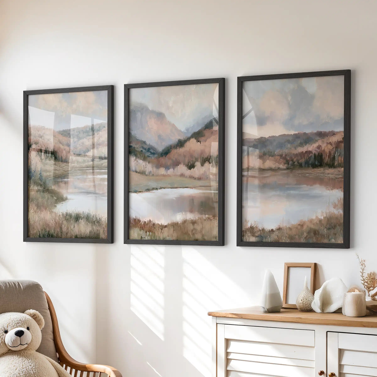 Three-piece wall art of moody hills above a calm lake, set in black frames, rests over the playroom dresser with hushed, painterly color.