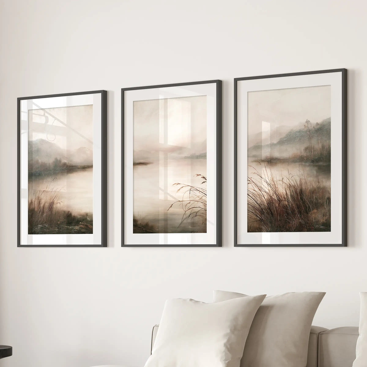 Misty lake landscape wall art set of 3 in black matted frames, hanging above a sectional in a sitting room.