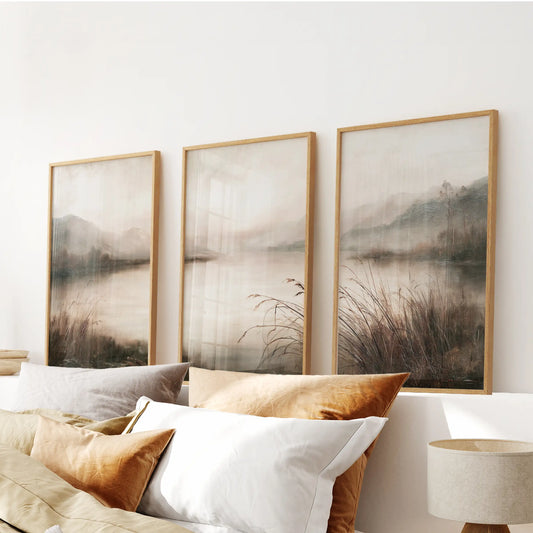 Set of three painterly nature wall hangings in light oak frames, arranged above the bed in a bedroom.