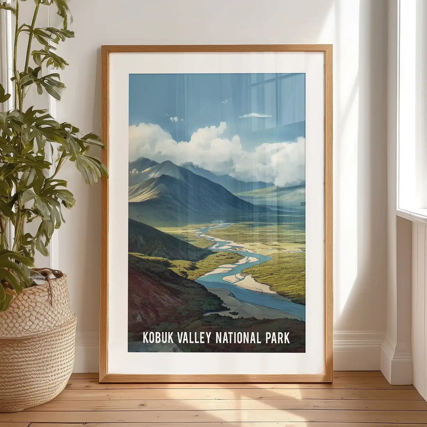 A large framed poster of mountain valleys rests on the bedroom floor near the bed, the black-matted print giving the space a quiet, northern scale.