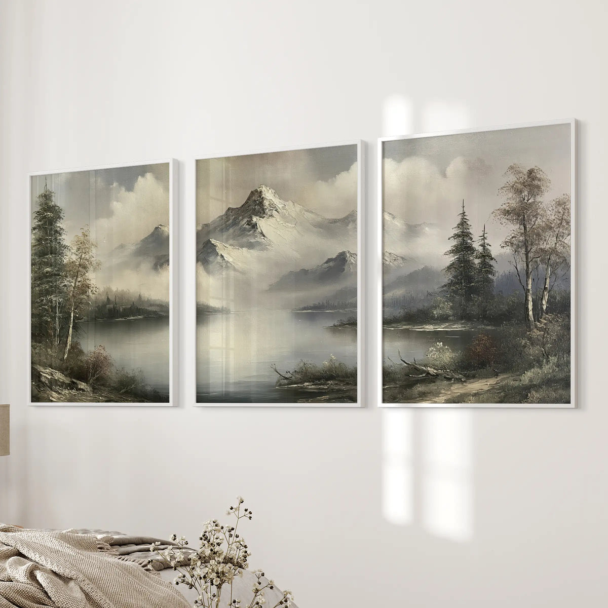 Wall art trio featuring muted alpine scenery in white frames, displayed in a horizontal row on a bedroom wall beside the bed.