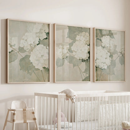 Vintage botanical florals appear in a three-piece wall picture set with natural oak frames, arranged above a cot in an infant room.