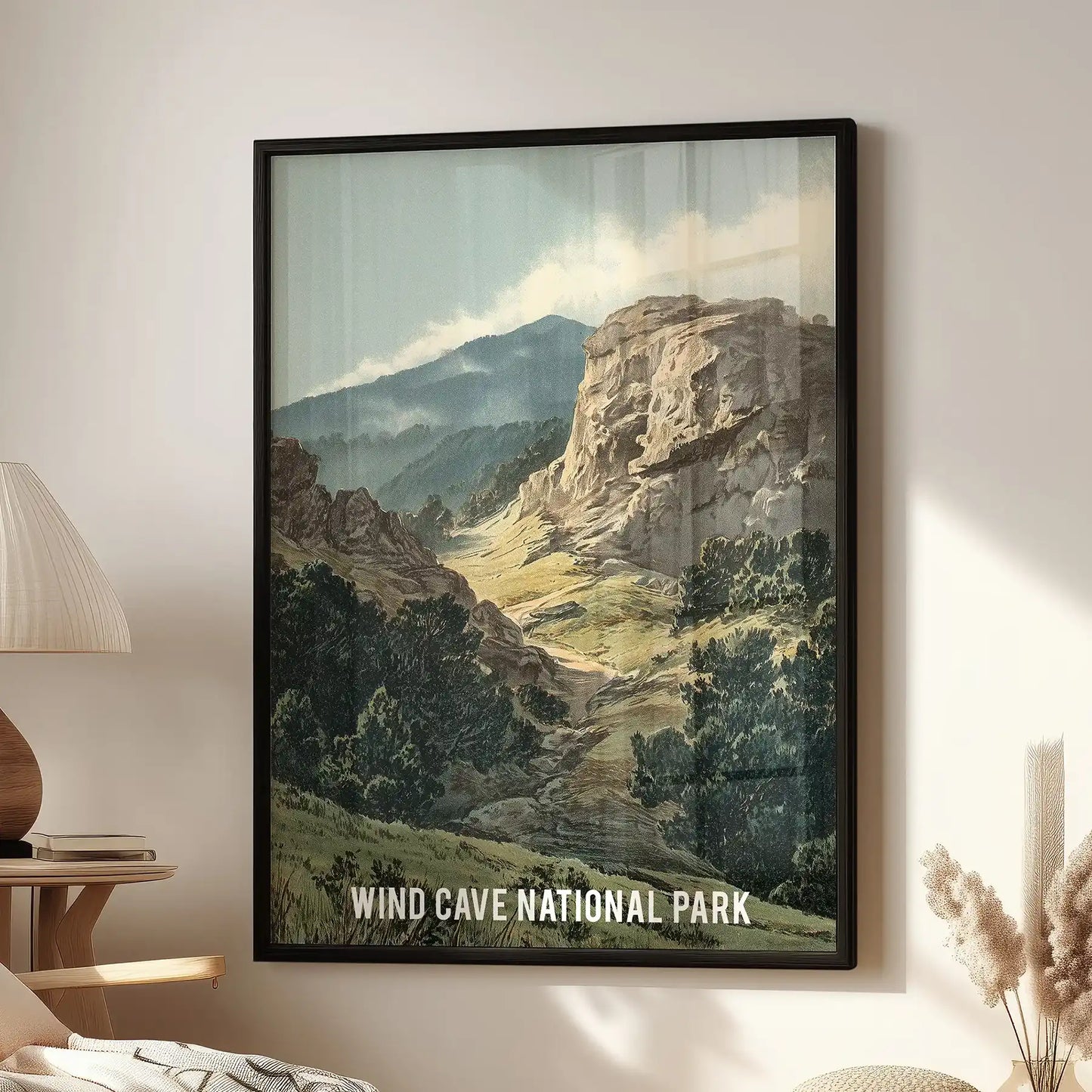 A black-framed Wind Cave National Park landscape poster hangs above a lounge chair, its rugged scene rendered in moody earth tones.