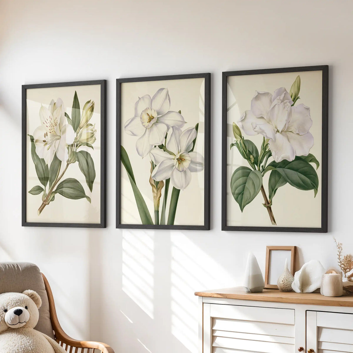 Above a dresser, three black-framed prints show white botanical flowers.