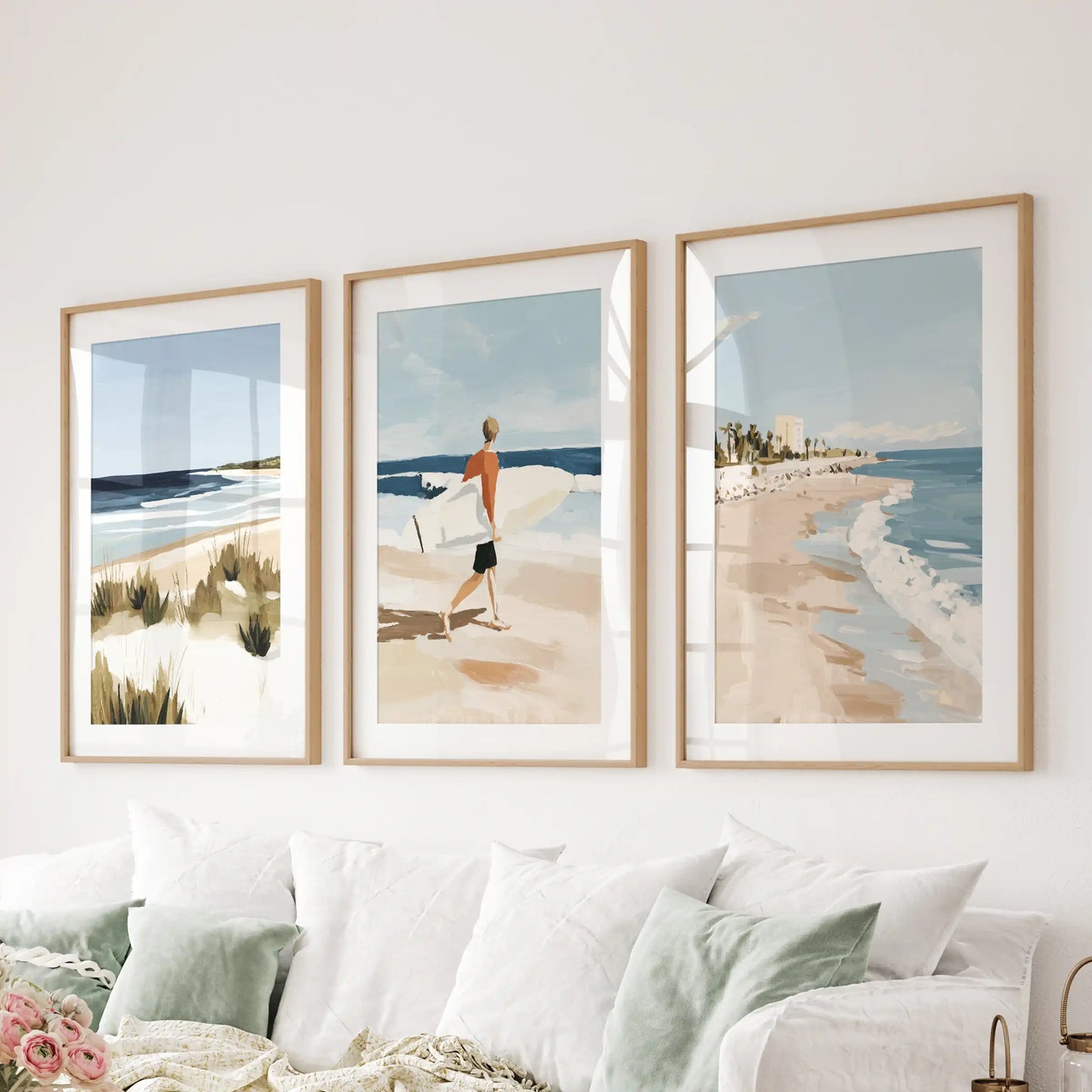 A set of three light-wood matted surf pictures spans the wall above the sitting-room sectional, adding gentle coastal rhythm.