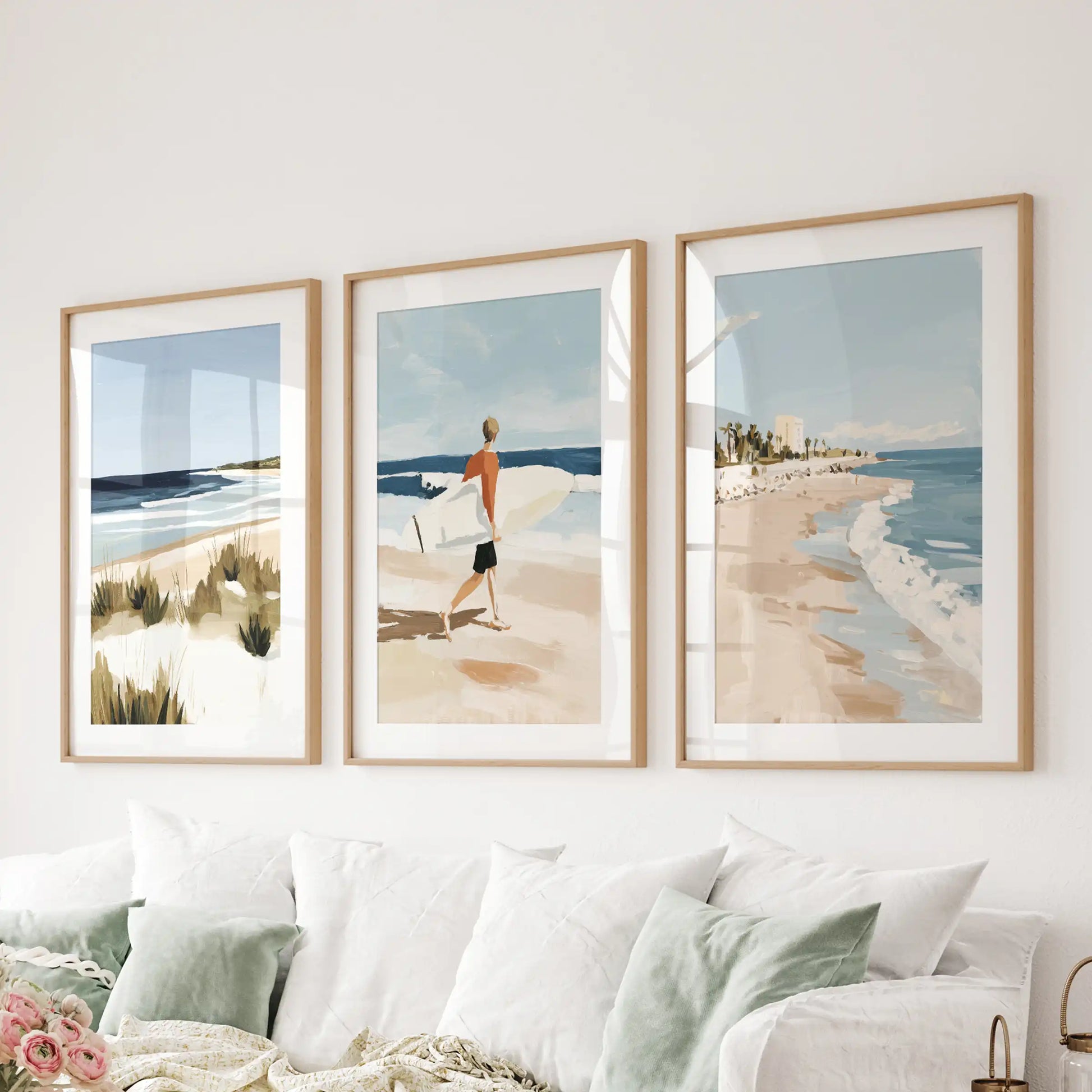 A set of three light-wood matted surf pictures spans the wall above the sitting-room sectional, adding gentle coastal rhythm.