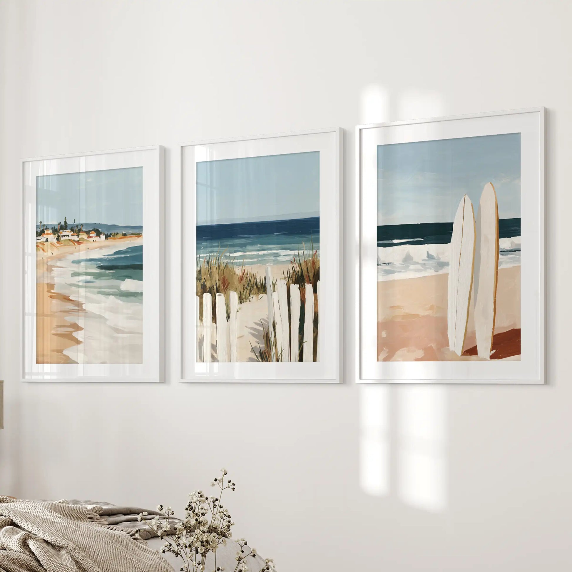 Surfboards on the beach print trio brings easy surf energy to the bedroom, mounted along the wall beside the bed in white frames with a wide mat.