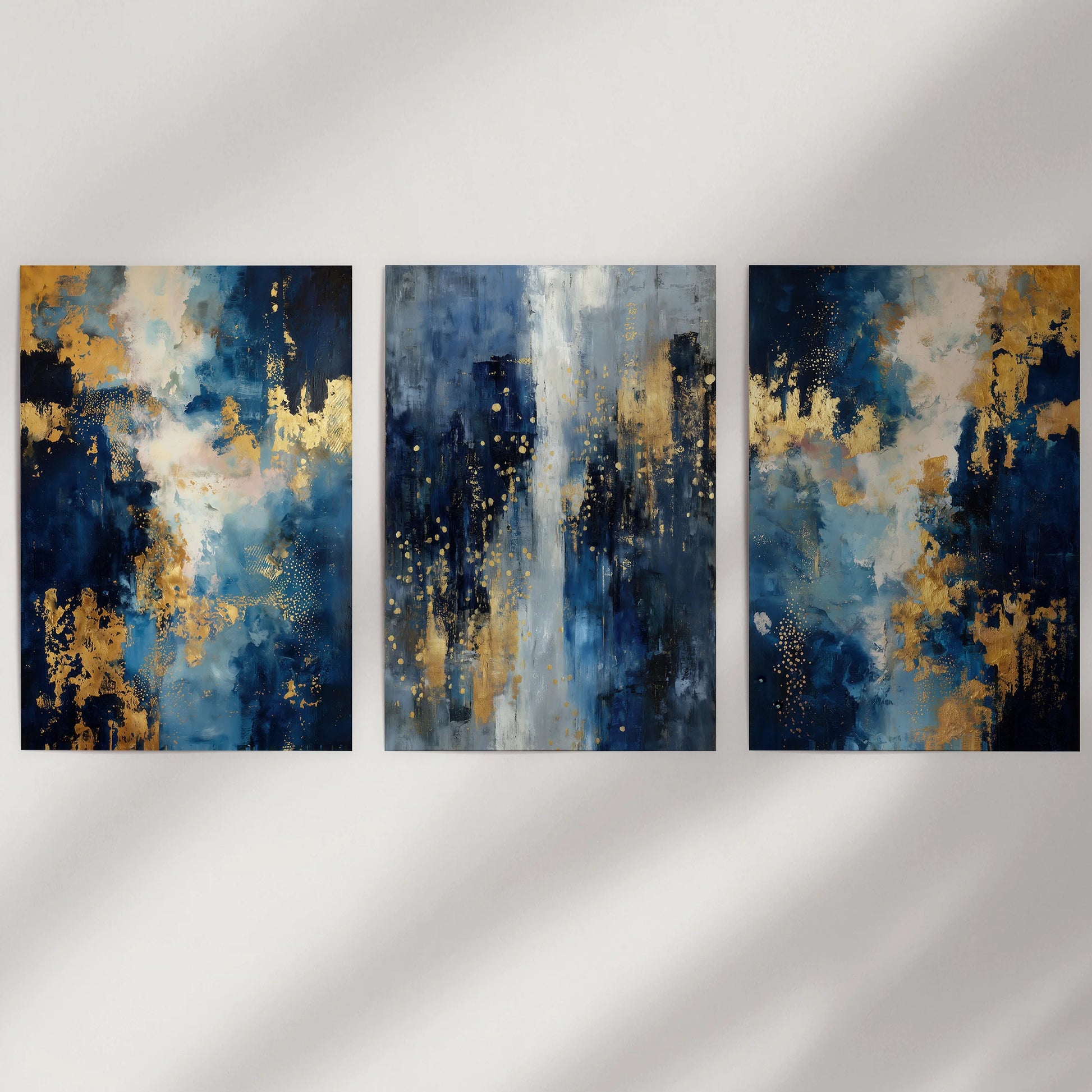 Three unframed wall panels with abstract navy forms and gold accents suit a minimalist wall, keeping the look crisp, modern, and uncluttered.