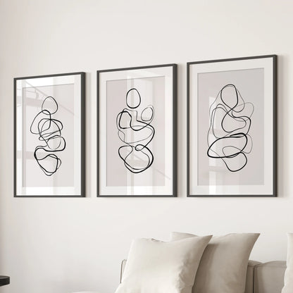 Neutral abstract-shape triptych wall decor, framed in black with wide mats, lends crisp balance to the lounge wall behind the sofa.