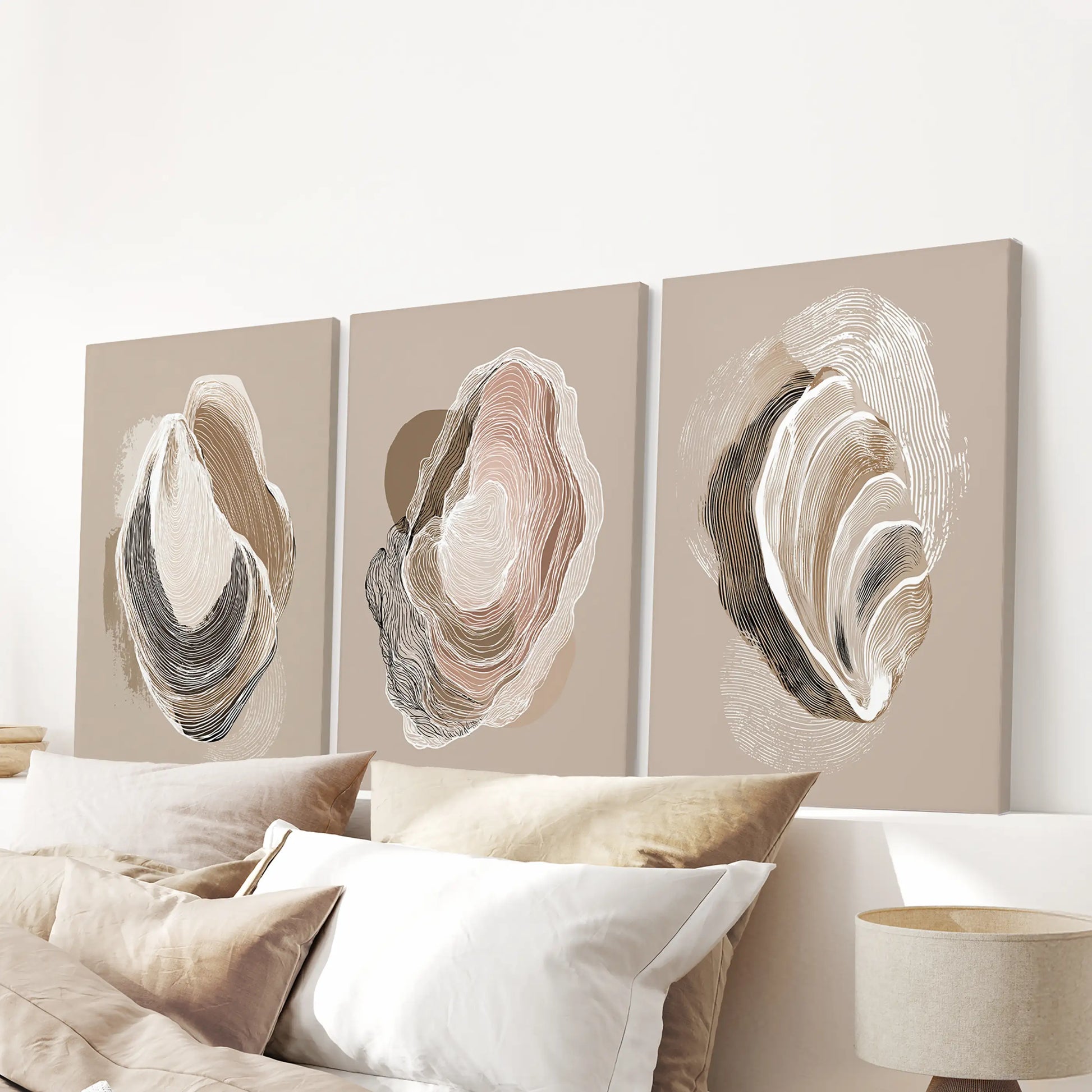 Minimalist shell illustrations, a set of three unframed canvases, hang above the bedroom bed for a subdued coastal accent in neutral beige.