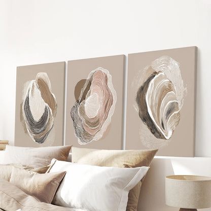 Minimalist shell illustrations, a set of three unframed canvases, hang above the bedroom bed for a subdued coastal accent in neutral beige.