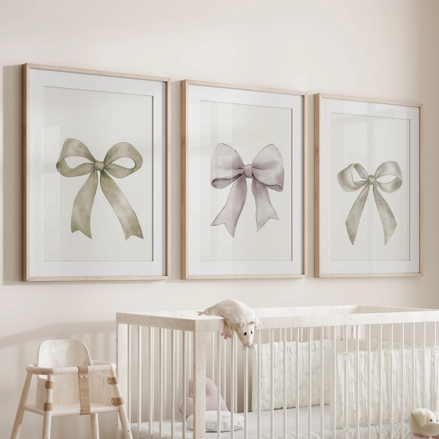 Cream ribbon posters, a three-poster set, hang over the nursery crib in wood-matted frames, pairing gentle bows with warm grain for a sweet, timeless look.