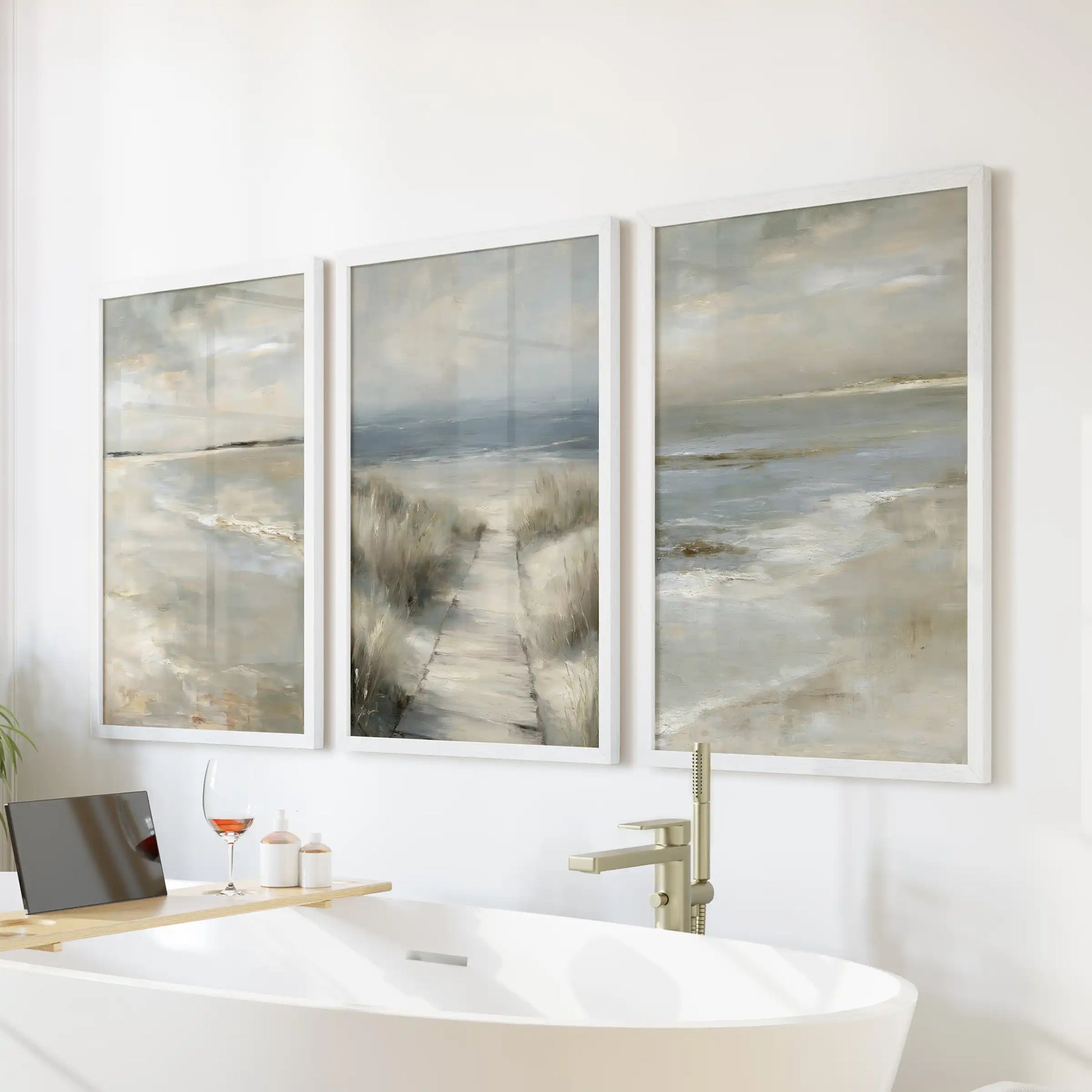 A three-panel white-framed wall art of a beach path through dunes hangs above the bath, giving the bathroom a spa-light coastal accent.