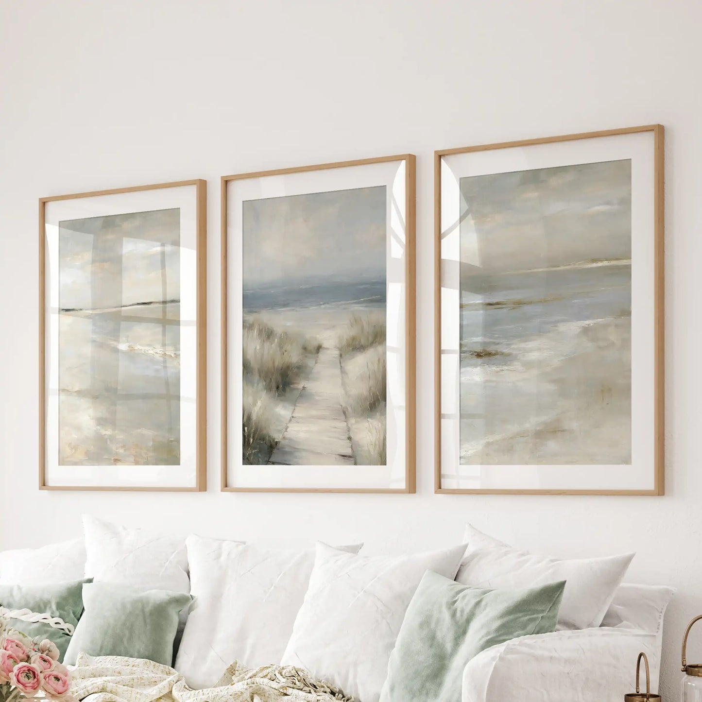 Serene ocean horizon three-piece wall hanging, in wooden frames with mats, stretches along the sitting room wall behind the couch.