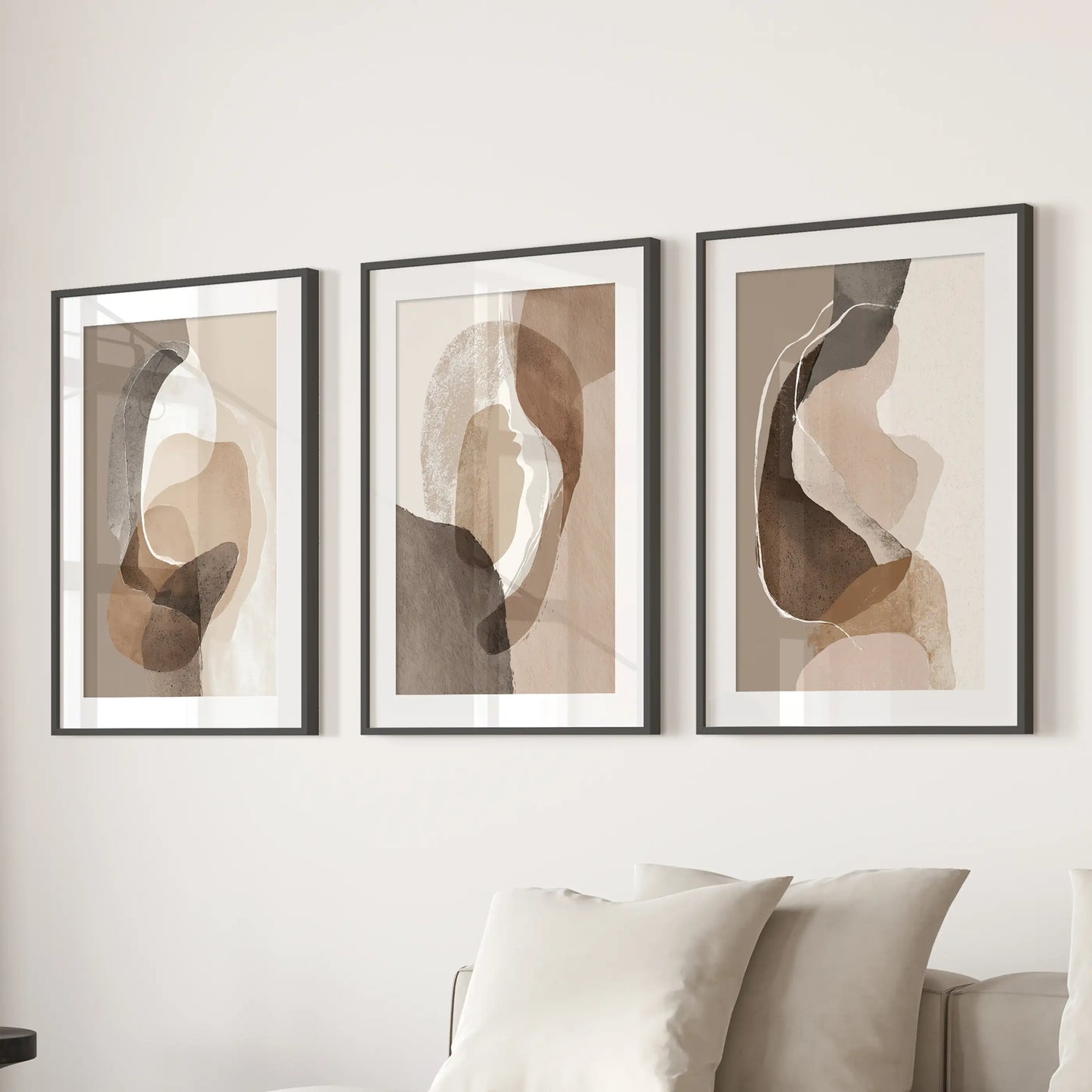 Earth-tone geometric prints three-piece set, in black frames with mats, hangs over the sectional to calm a sitting room with layered neutrals.