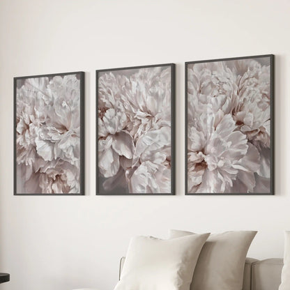 Above a sofa, three prints in black frames show densely layered peony petals filling each picture.