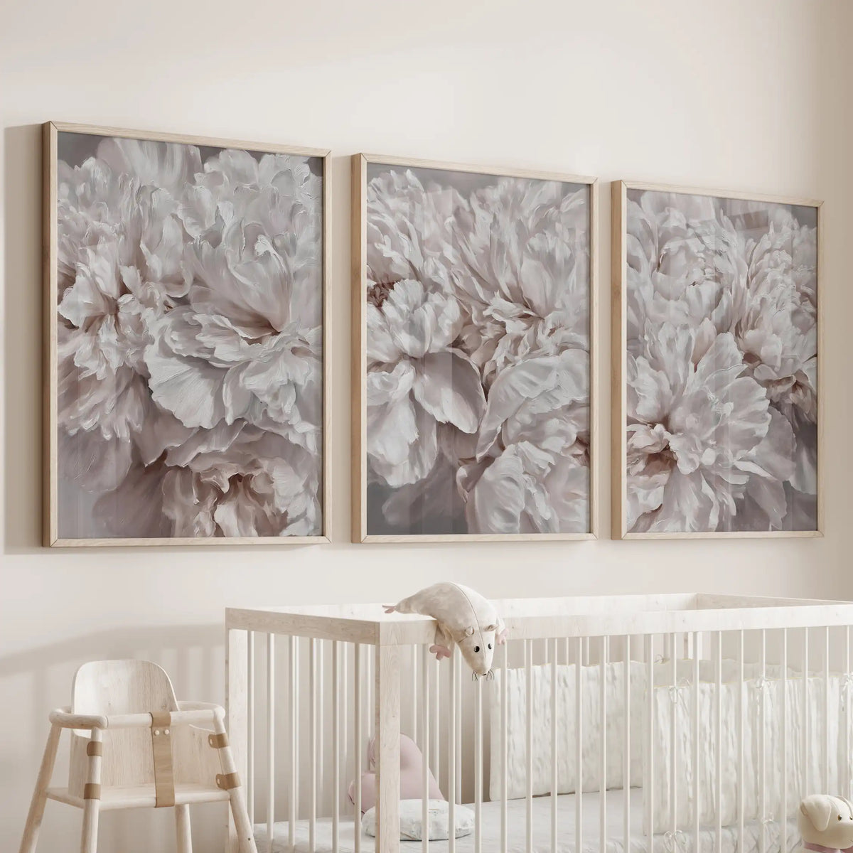 The three oak-framed prints above a crib are filled with densely layered peony petals in pale pink and ivory, with no stems in view.