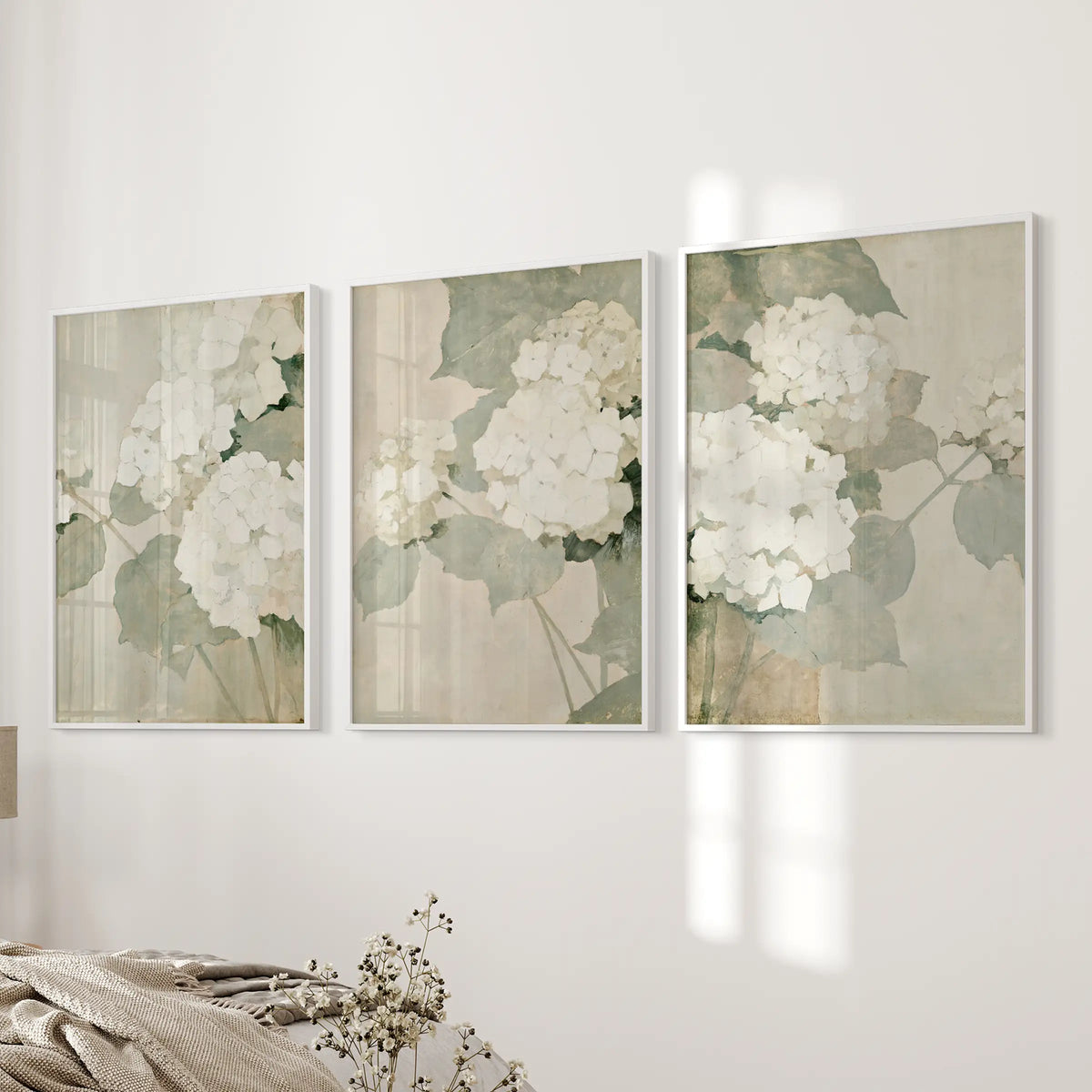 Vintage garden botanicals make up a set of three wall art prints in white frames, displayed on the bedroom wall beside the bed.