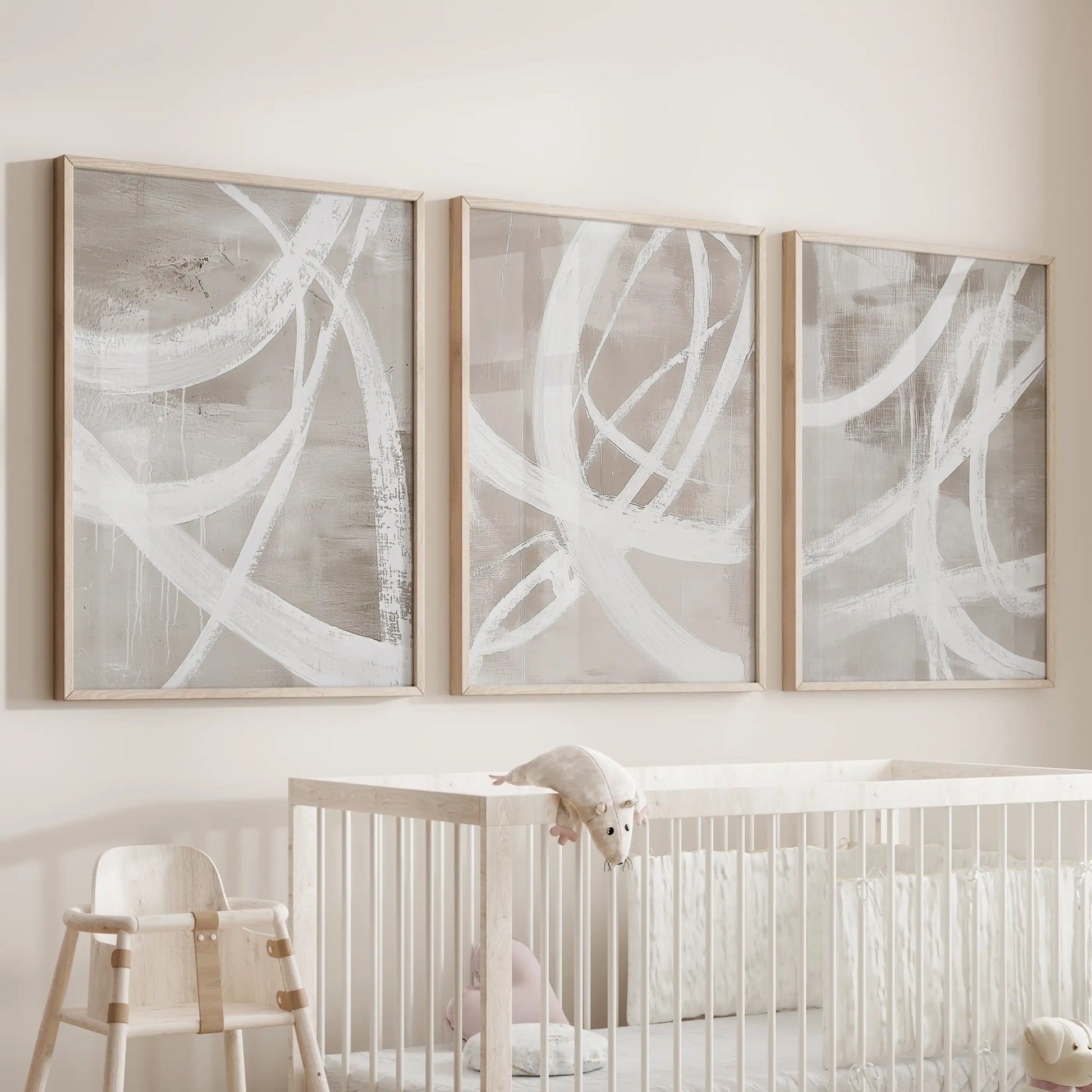 A trio of wood-framed pictures with gentle organic shapes hangs above the cot, adding a tender, natural note to the baby room.