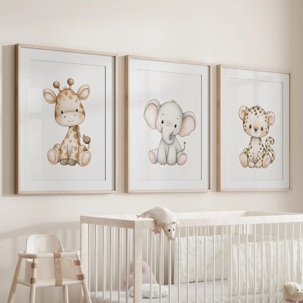 Above a white crib, oak frames with white mats hold three prints of seated baby animals: a giraffe, a gray elephant and a spotted leopard.