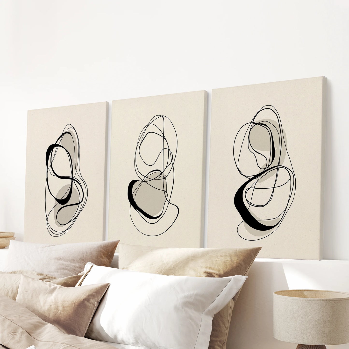 A gallery-wrapped three-piece wall art set in clean neutral tones, balancing the space above the bed headboard with quiet modern polish.