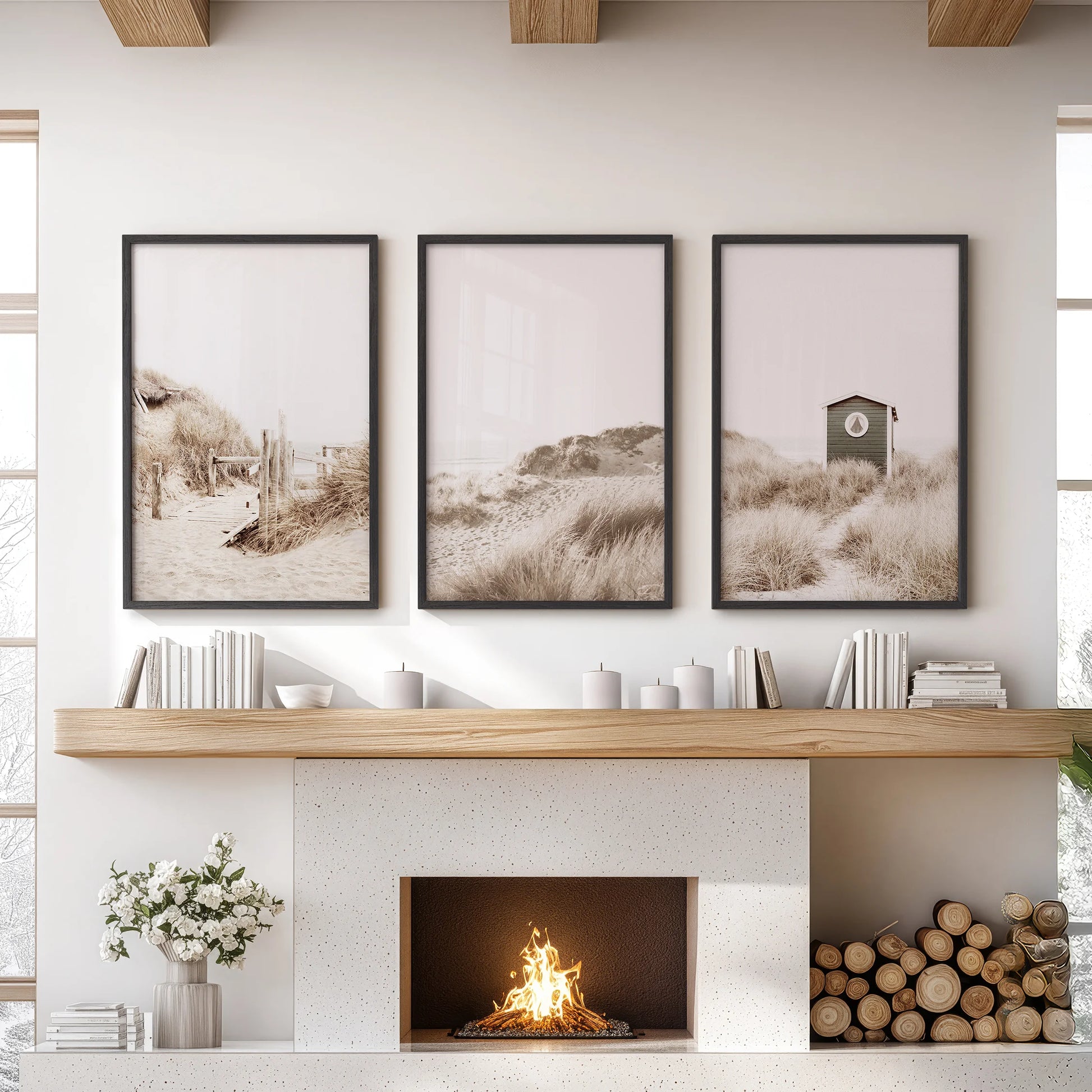 A trio of black-framed wall prints shows a sunlit beach path above the lounge mantel, bringing airy dunes and a calm coastal mood.